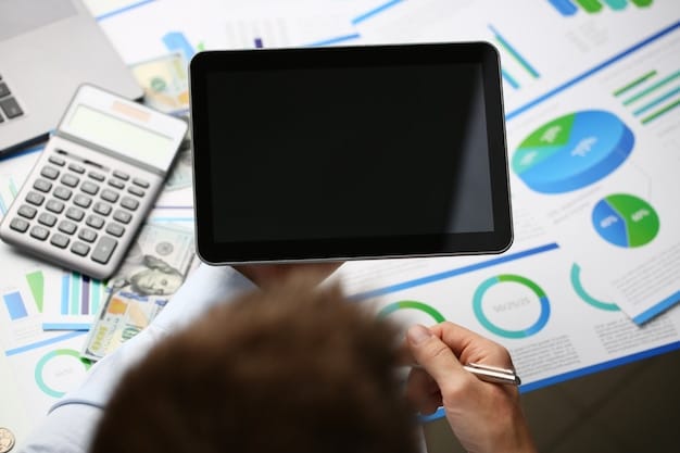 A person carefully reviewing financial documents and using a calculator, with a laptop displaying charts and graphs in the background.