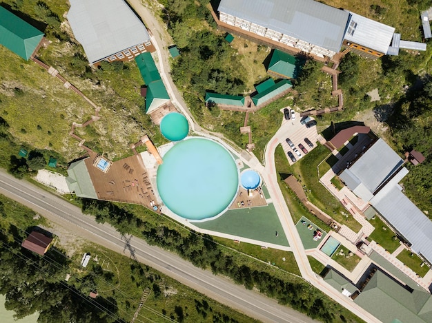 Drone view of a modern water treatment plant with large sedimentation tanks and filtration systems, located next to a clean river and surrounded by trees and green fields.