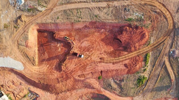 An aerial shot of a large iron ore mine in Brazil, showing the vast scale of the operation with trucks and equipment moving around the site. Dust and tailings are visible, highlighting environmental concerns.