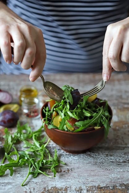 A close-up, vibrant shot of hands preparing a healthy salad. Fresh greens, colorful vegetables, and a light dressing are being mixed in a wooden bowl. The background is blurred, creating a focus on the ingredients and the act of making a wholesome meal.