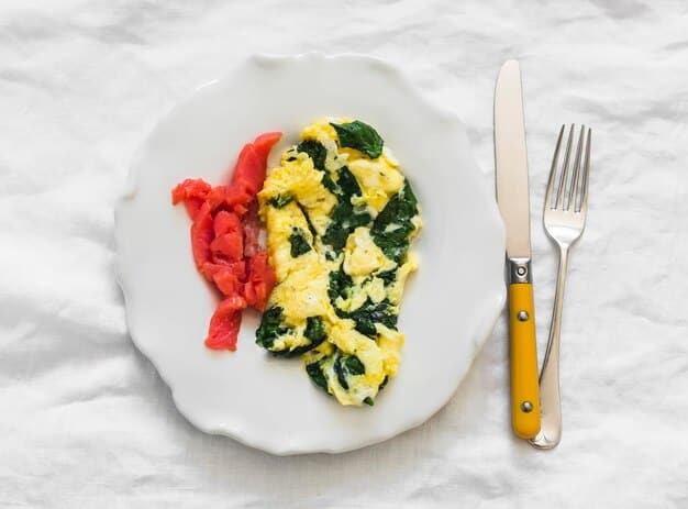 An overhead shot of a colorful breakfast table. A vibrant omelet filled with spinach and cherry tomatoes is the centerpiece, accompanied by a side of fresh berries and a glass of orange juice. The setting is bright and inviting, emphasizing the healthiness and appeal of the meal.