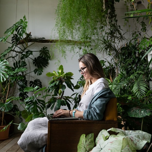 A young woman smiling confidently as she works on a laptop in a co-working space, surrounded by plants and natural light, symbolizing personal growth and digital skills.