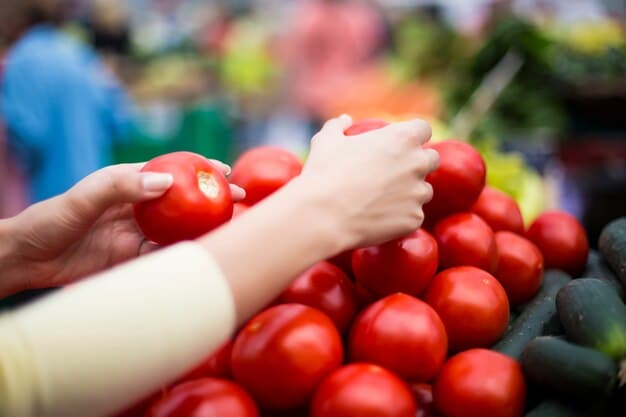 A person's hands selectively picking vibrant, organic tomatoes at a local farmers market. The focus is on the freshness and quality of the produce, highlighting the direct connection between the consumer and the source of organic farming. The lighting is bright and natural, emphasizing the colors and textures of the tomatoes.