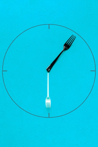 A digital clock displaying the time 4:00 PM, with a fork and knife overlaid on the image, symbolizing the 16/8 intermittent fasting method's eating window.
