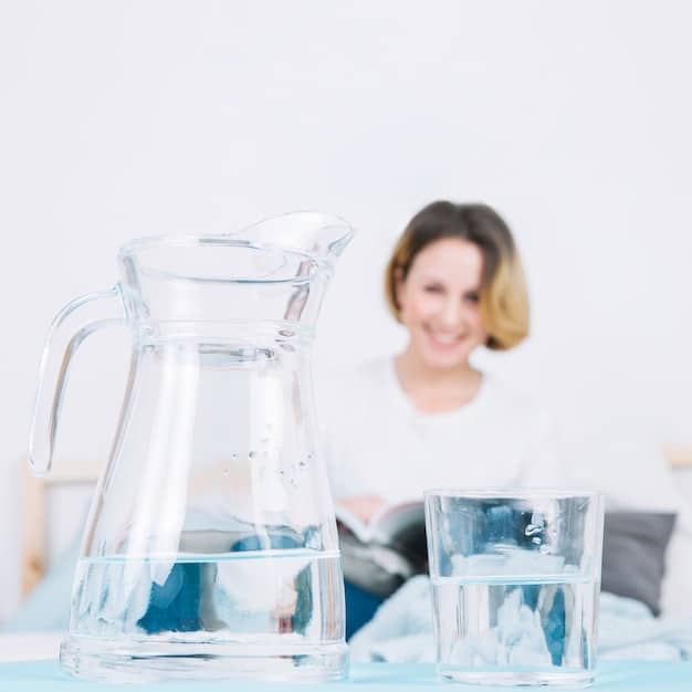 A person filling a glass with water from a water filter pitcher, emphasizing the importance of hydration during intermittent fasting.
