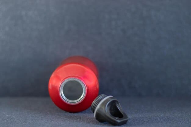 A bird's-eye view of a sports water bottle and a handful of energy gels on a colorful running track. The track is slightly blurred in the background, giving a sense of speed and motion, while the focus remains sharp on the hydration and energy supplements.
