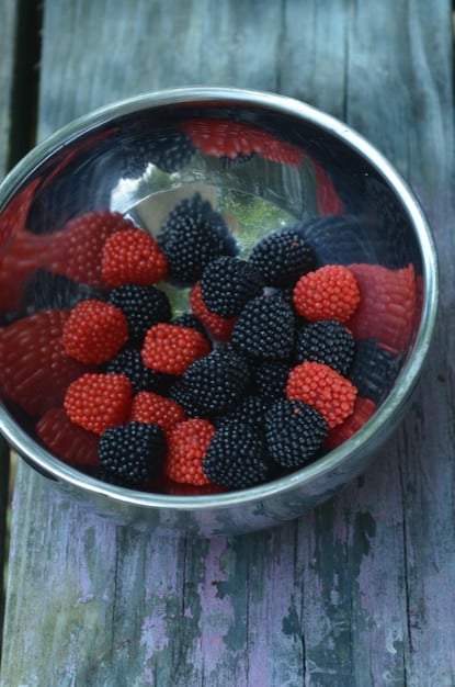A close-up shot of a bowl brimming with colorful berries like blueberries, raspberries, and strawberries, highlighting their vibrant colors and textures, with a soft, natural light to emphasize their freshness.