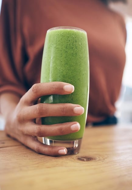Close-up shot of a hand pouring a vibrant green smoothie from a blender into a glass, with fresh spinach, kale, apple slices, and lemon wedges scattered around, emphasizing the use of whole, natural ingredients for a healthy detox drink.