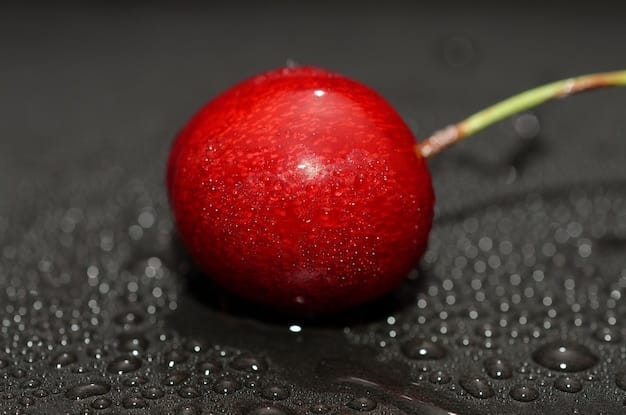 A close-up shot of acerola cherries, both whole and cut in half, showing their vibrant red color and juicy texture. A few green leaves surround the cherries, emphasizing their freshness and natural source of vitamin C.